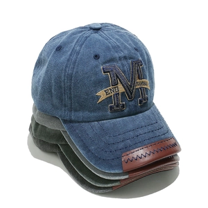 Detail of vintage washed cotton baseball caps with M embroidery and leather brim accent
