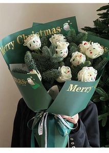 Close-up of luxury dark green gold-stamped Christmas bouquet wrap with roses and pine
