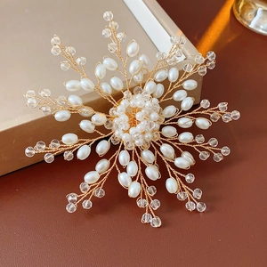 Macro shot of snowflake brooch with woven pearls and gold wire on leather surface