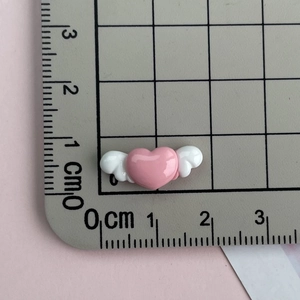 Macro detail of pink winged heart resin charm with ruler showing 2.5cm size