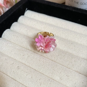 Vista macro di un anello dorato regolabile con delicati petali di fiori in resina