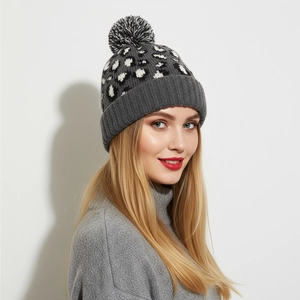 Detail of leopard print knit beanie featuring a large faux fur pompom and ribbed cuff
