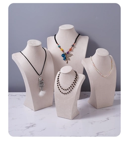 Detailed set of four cream velvet necklace display busts in various sizes and heights