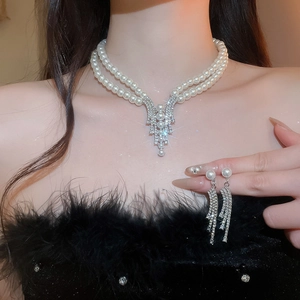 Detail of elegant pearl necklace with V-shaped rhinestone pendant and matching earrings