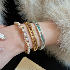 Gros plan de bracelets ethniques perlés et joncs vintage portés par un mannequin