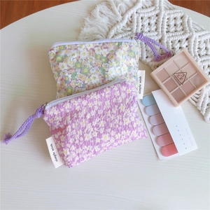 Détail de mini porte-monnaie en coton à fleurs violettes et crème sur un bureau blanc
