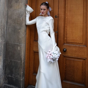 Detail of elegant white satin gown featuring flared sleeves and a minimalist bridal style
