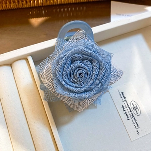 Dettaglio ravvicinato della pinza per capelli con rosa in pizzo blu e petali a strati