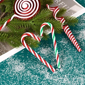 Red, white, and green Christmas candy cane and lollipop hanging ornaments on snowy pine