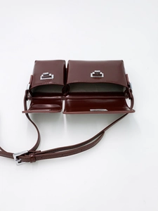 Top view of reddish-brown twin-compartment crossbody bag with glossy leather and silver buckles