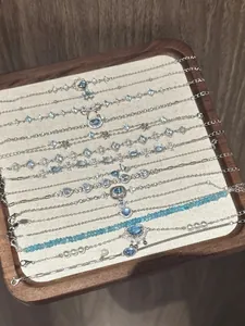 Detail view of dainty silver bracelets with blue zircons and pearls on a wooden display