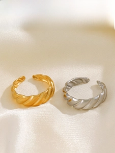 Detailed close-up of twisted croissant rings in gold and silver on silk fabric