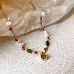 Detail of baroque pearl necklace with green gemstone pendant and 18k gold plating