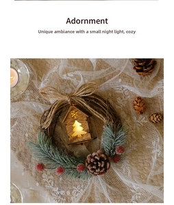 Detail of Christmas wreath with pine cones, red berries and a glowing wooden house