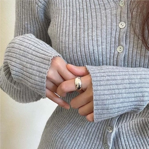 Close-up of minimalist silver wide band ring worn with casual grey knitwear
