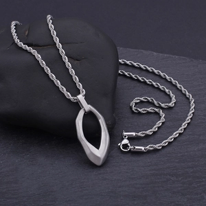Detail of silver drop-shaped pendant on twisted chain over grey textured stone