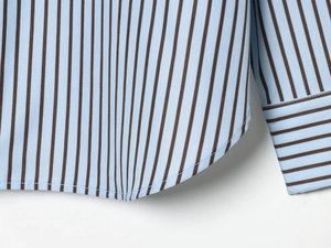 Detail of blue and brown striped poplin shirt showing curved hem and fine stitching