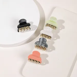 Macro view of five mini acrylic hair claws in black, green, white, grey, and pink colors