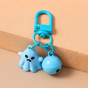 Detail of blue cartoon ghost keychain with matching bell on a textured foam block