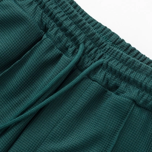 Detalle de pantalones cortos de punto gofrado verde oscuro con cintura elástica y cordón