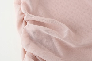 Detailed close-up of soft pink mesh fabric with delicate pleated textures and breathable holes