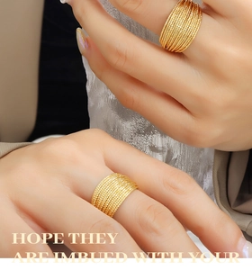Close-up of a gold-plated multi-layer textured ring on a hand with luxury background