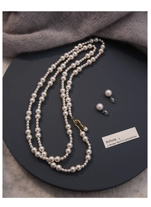 Détail d'un ensemble collier de perles de luxe et boucles d'oreilles sur textile gris