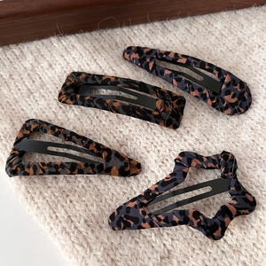 Set of 4 vintage leopard print hair clips in geometric shapes on a soft knit background