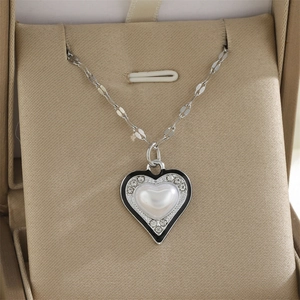 Détail du collier cœur avec émail noir, perle blanche et cristaux sertis en pavé
