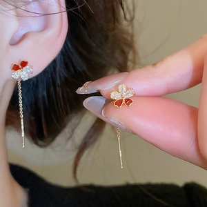 Macro shot of gold-plated flower tassel earring with red petals and zircon details