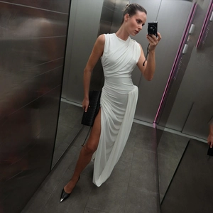 Close-up of white sleeveless maxi dress featuring elegant ruching and a high side slit