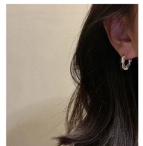 Macro shot of silver twisted knot hoop earring on model with polished metal finish