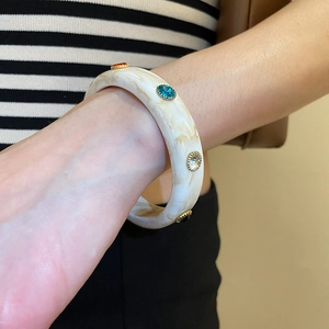 Close-up of wide acrylic bracelet with marbled texture and colorful rhinestones