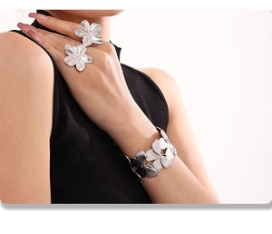 Macro view of silver floral ring and bangle set showing brushed metal texture on skin