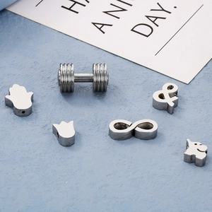 Assorted DIY jewelry charms including dumbbells and infinity signs on blue surface