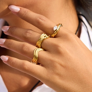 Three-piece gold titanium steel ring set with wavy patterns and teardrop crystal detail