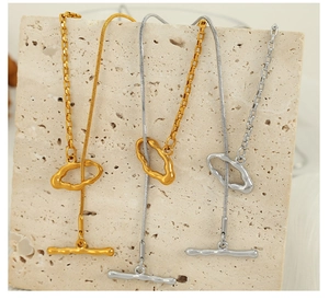 Detail showing three irregular OT buckle necklaces in gold and silver on stone texture