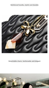 Detail of black wave-quilted leather tote with golden bow and amber resin charm