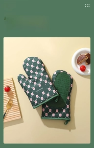 Close-up of green heat-resistant oven mitts with floral pattern and silicone grip
