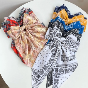 Flat lay of colorful paisley print silk bow hair clips on a white circular surface