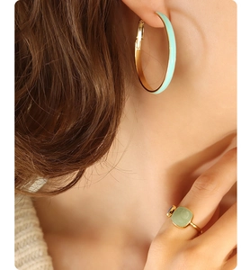Detail of mint green enamel hoop earrings and matching square stone ring on model