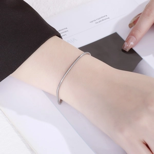 Close-up of minimalist silver snake chain bracelet with adjustable pull-bead on wrist