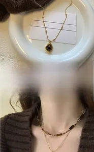 Detail of vintage gold necklace with brown stone pendant and beaded chain layering