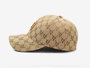 Detail of beige baseball cap featuring vintage letter patterns and an orange leather patch