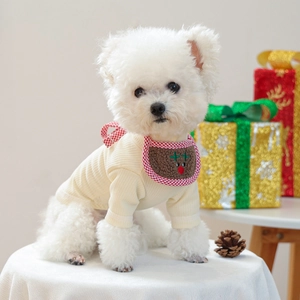 Close-up of a dog wearing a beige knitted sweater and reindeer plaid Christmas bandana