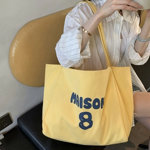 Large yellow canvas tote bag with blue Maison 8 text shown on a model's shoulder