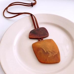 Detail of a vintage horn-style pendant featuring amber marble resin on a ceramic plate