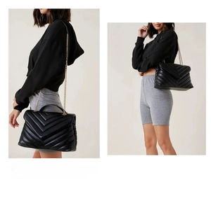 Detail view of black quilted V-pattern leather crossbody bag with gold chain strap