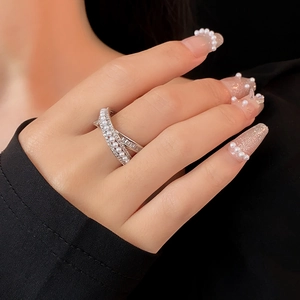 Detail of zircon and pearl criss-cross ring showing sparkling stones on a model hand