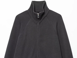 Detail of dark grey knit cardigan showing zipper and fine ribbed stitching texture
